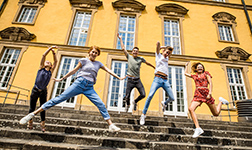 Fünf Studierende im vollen Sprung von der Treppe des Schlosses der Universität Osnabrück